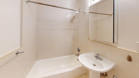 A white bathroom with a tub, sink and mirror.
