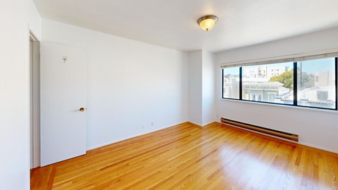 A room with wooden floors and a window overlooking a cityscape.