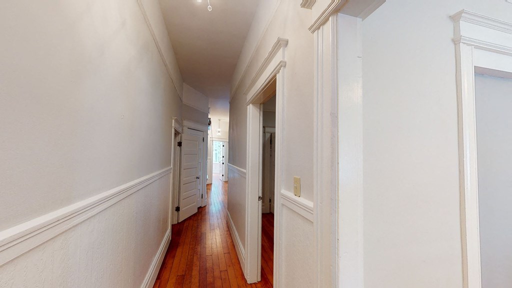 a long hallway with white walls and wood floors