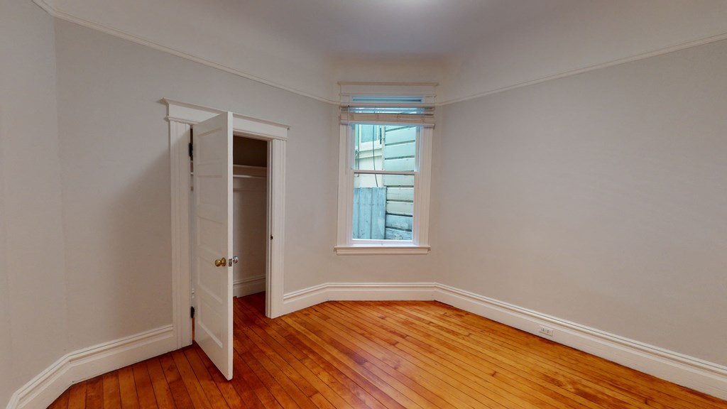 a bedroom with wood floors and a door to a closet
