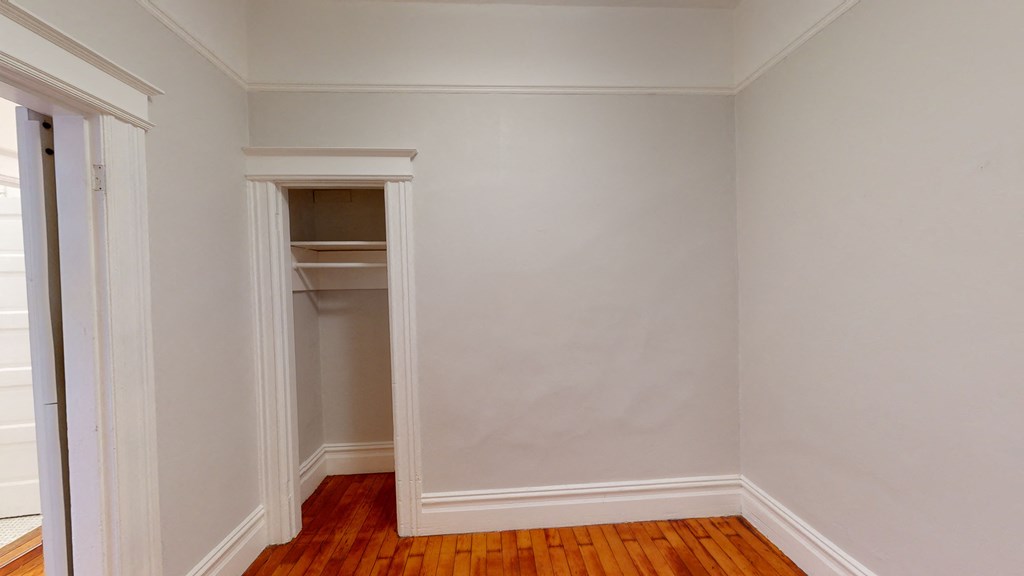a room with white walls and a closet and a wooden floor