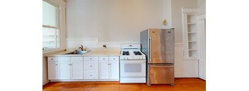 an empty kitchen with white cabinets and a stainless steel refrigerator