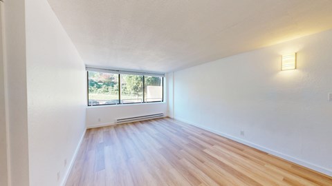 Empty room with a window and a wooden floor.