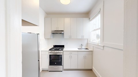 A kitchen with white cabinets and a stainless steel refrigerator.