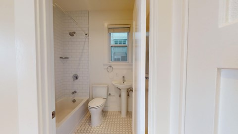 A white bathroom with a toilet, sink, and bathtub.