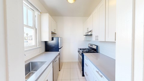 A kitchen with white cabinets and a black fridge.