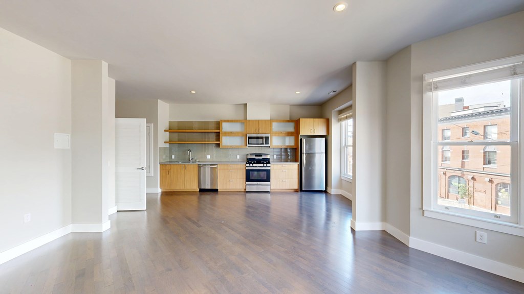 A spacious kitchen with wooden floors and white walls.