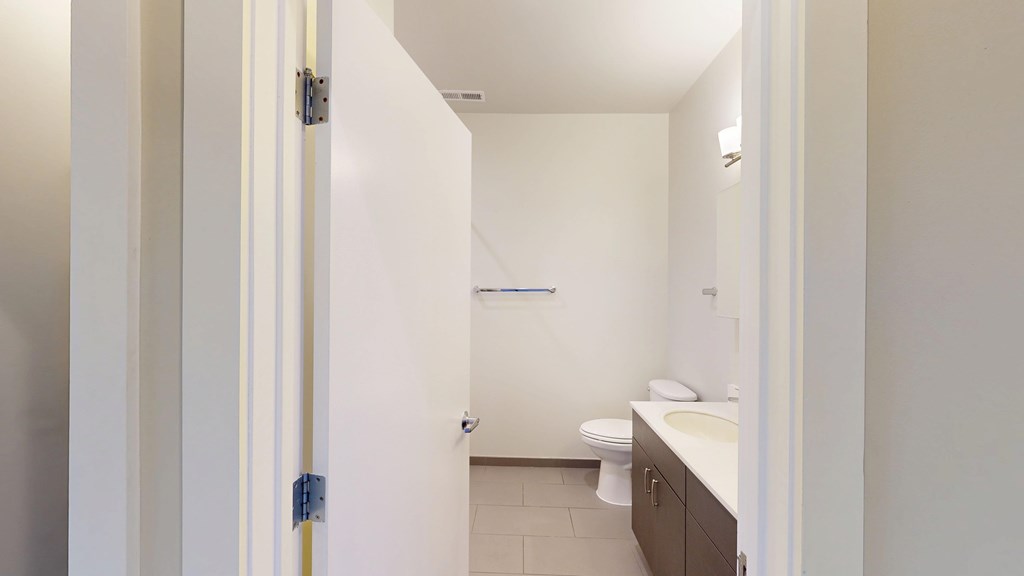 A bathroom with a toilet, sink, and mirror.