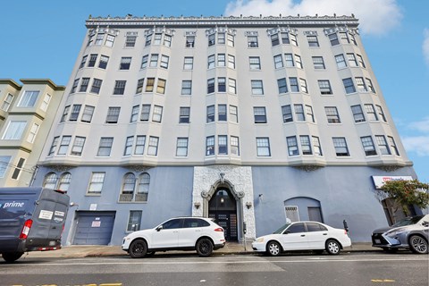 A white car is parked in front of a blue building.