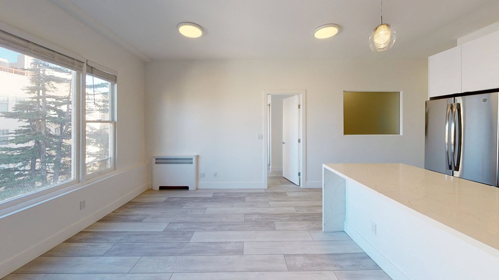 an empty kitchen with white cabinets and a large window