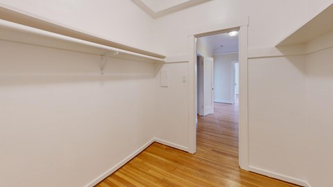 A hallway with a white wall and a wooden floor.