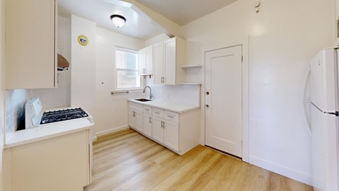 A kitchen with white cabinets and a white fridge.