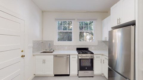 A kitchen with white cabinets and a stainless steel refrigerator.