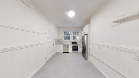 A kitchen with white cabinets and a stainless steel refrigerator.