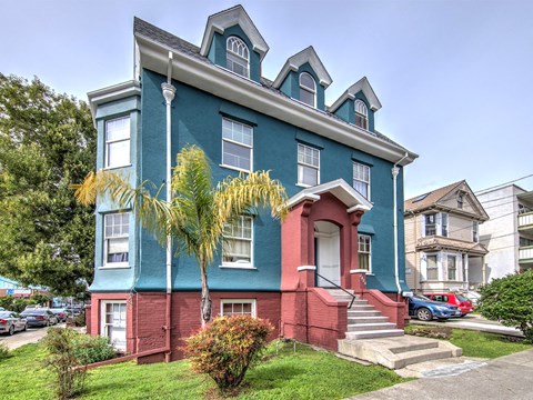 A blue house with a red door and steps leading up to it.