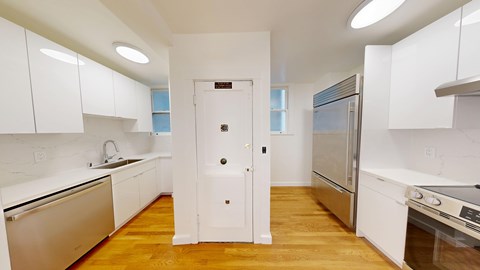 A kitchen with white cabinets and a wooden floor.