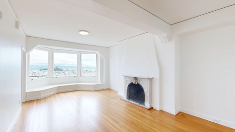 A white room with a fireplace and a window overlooking the beach.