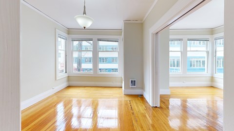 A room with wooden floors and a large window overlooking a city.