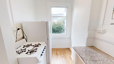 A white gas stove in a kitchen with a window.