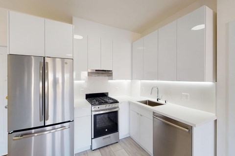 A modern kitchen with white cabinets and stainless steel appliances.