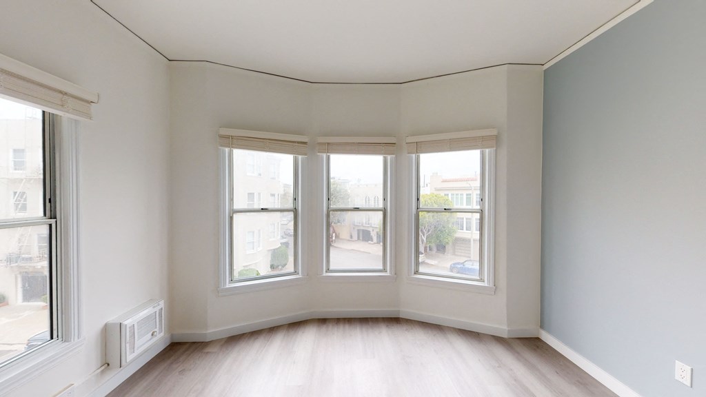 an empty living room with three windows and a wood floor