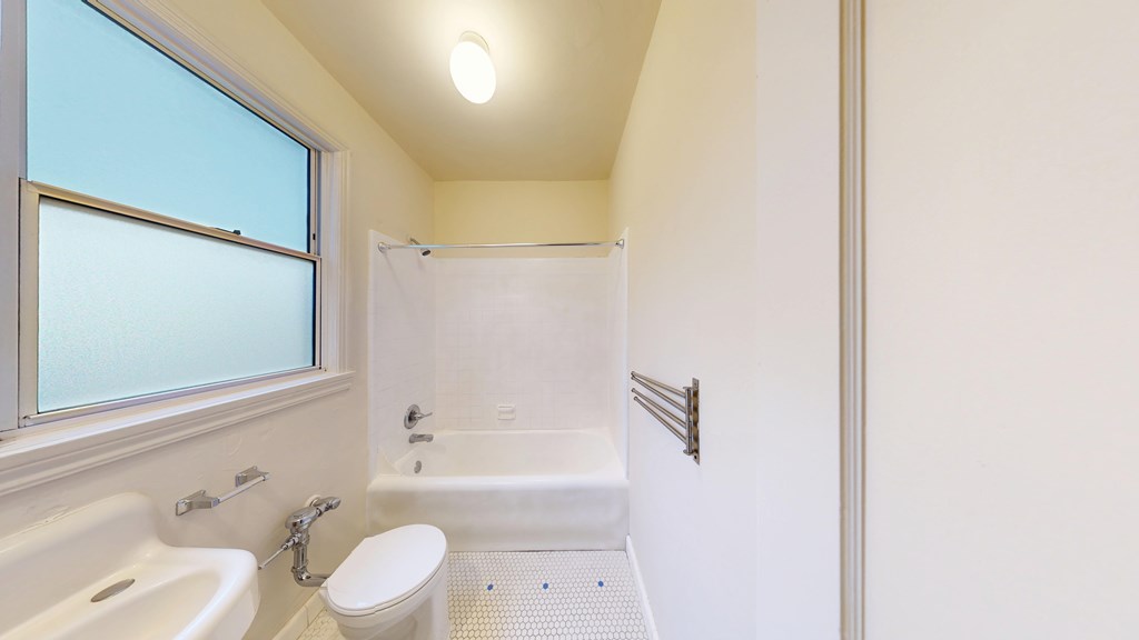 A white bathroom with a tub, toilet, and sink.