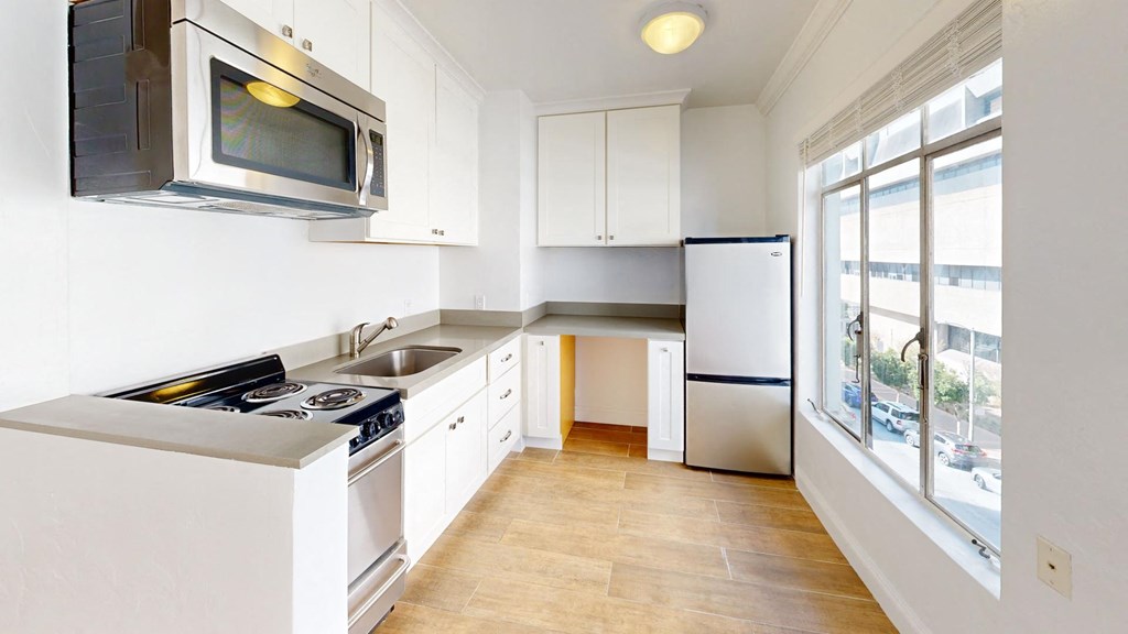 a kitchen with white cabinets and a window
