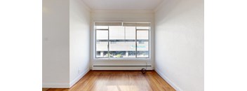 an empty room with a window and wooden floors