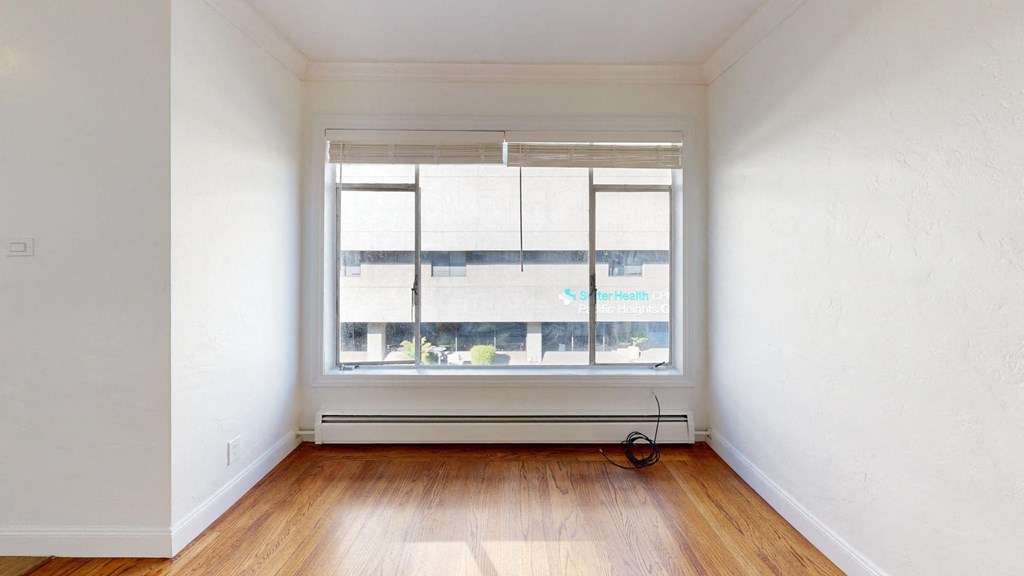an empty room with a window and wooden floors