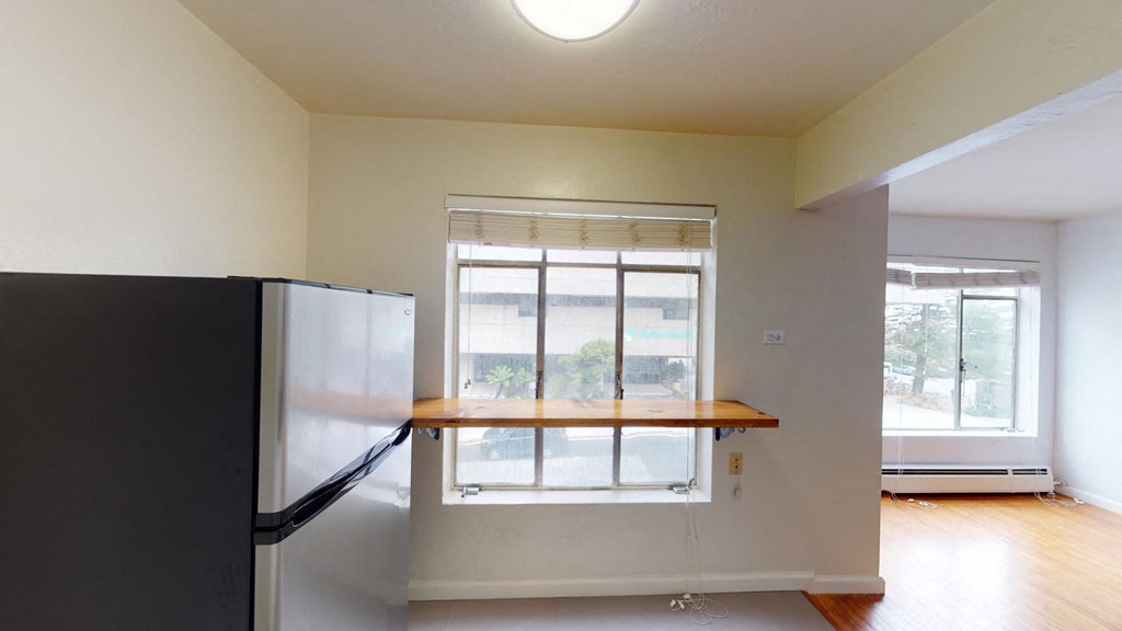 an empty room with a window and a refrigerator