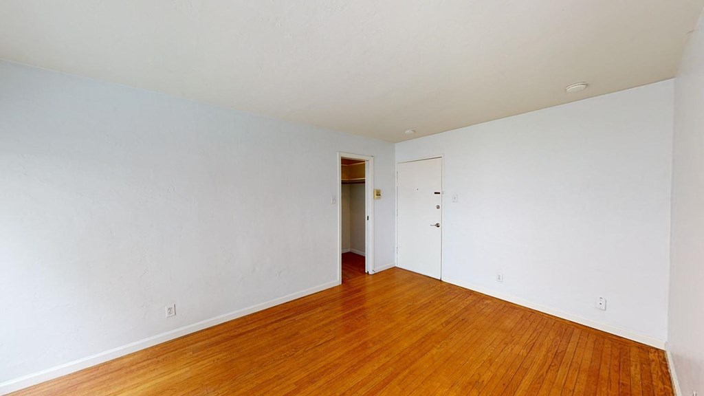 an empty living room with white walls and wood floors