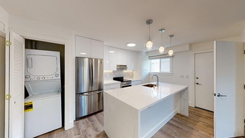 a white kitchen with a large island and stainless steel appliances