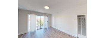 an empty living room with white walls and a sliding glass door