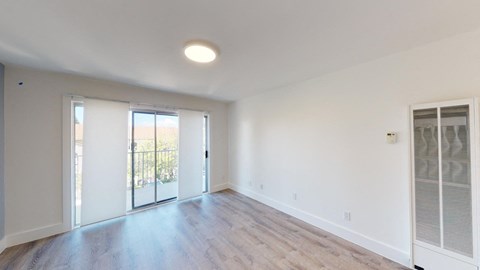 an empty living room with white walls and a sliding glass door