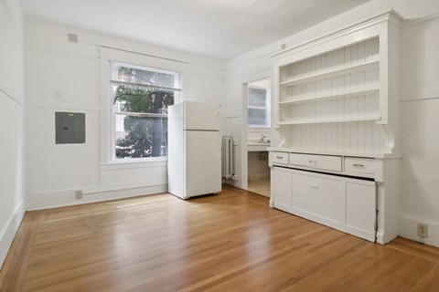 A kitchen with white cabinets and a wooden floor.