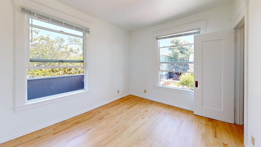 A room with wooden floors and two windows.