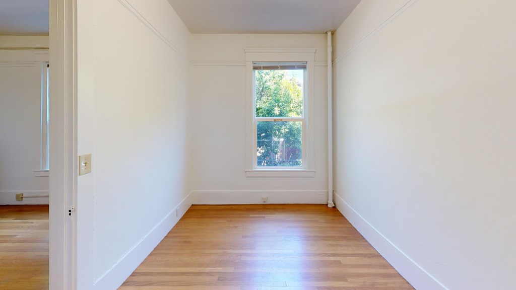 A room with a window and wooden floors.