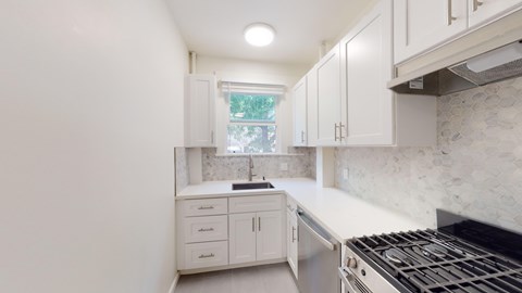 A kitchen with white cabinets and a black stove top.