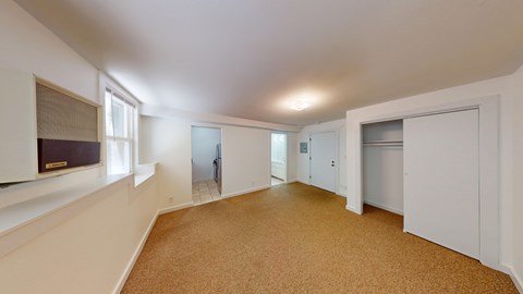 A spacious room with white walls and carpeted floor.