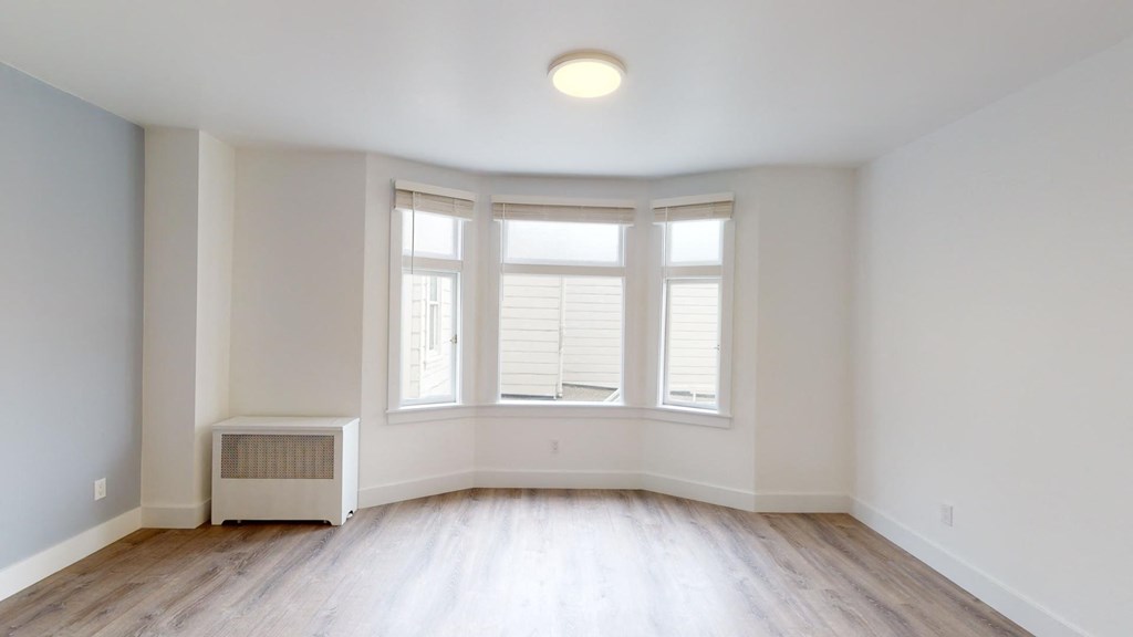 the living room of an empty house with white walls and a large window