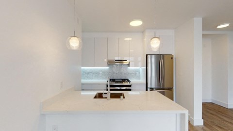 a kitchen with a white counter top and a stainless steel refrigerator