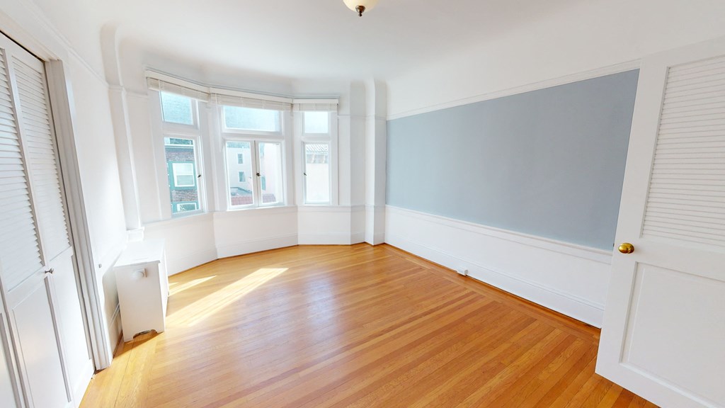 an empty living room with wood floors and a blue wall