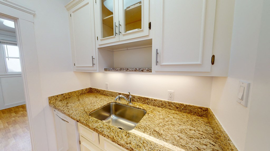 a kitchen with white cabinets and granite counter top and a sink