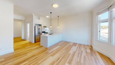 an open kitchen and living room with wood floors and white walls
