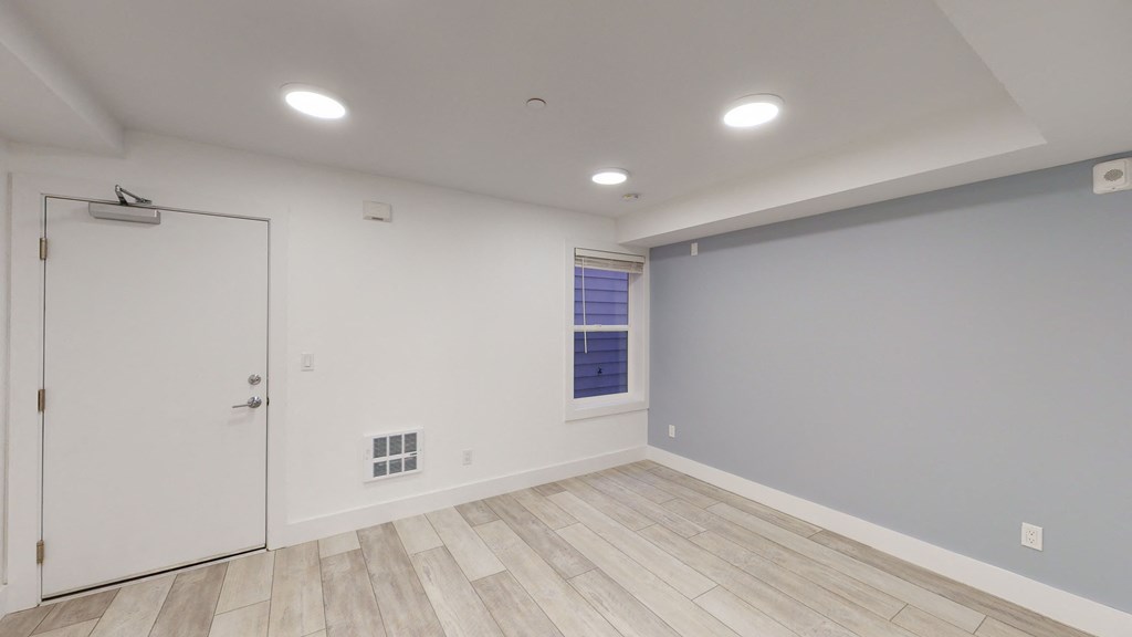 a living room with white walls and wood floors and a white door