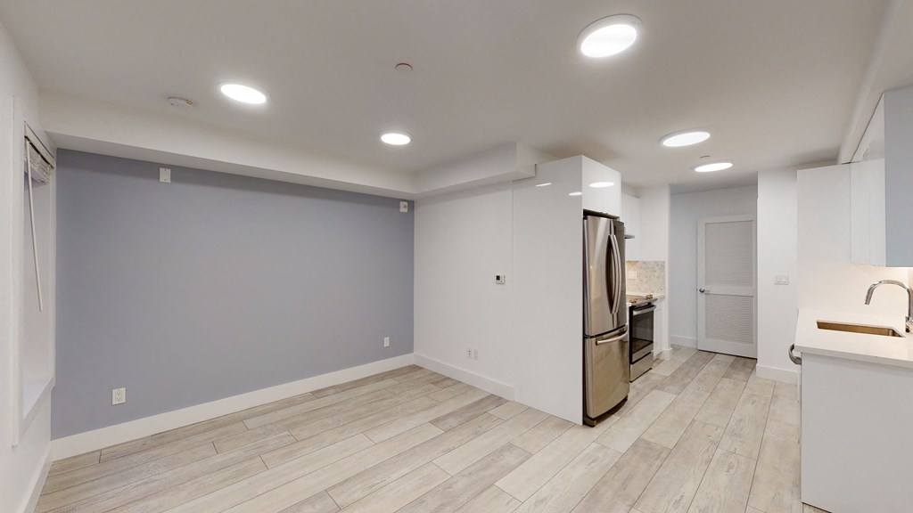 the living room and kitchen in a new home with grey walls and wood flooring
