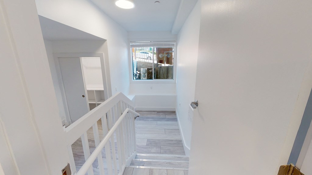 a look down the stairwell of a home with a window and a white staircase