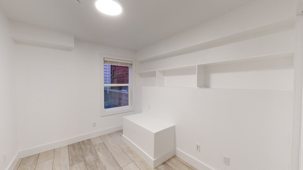 a living room with white walls and white furniture and a window