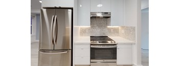 a white kitchen with stainless steel appliances and white cabinets