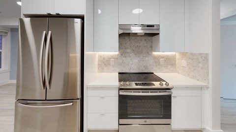 a white kitchen with stainless steel appliances and white cabinets
